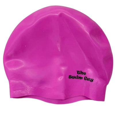 Pink swim cap with 'The Swim Guy' logo on a gray floor.