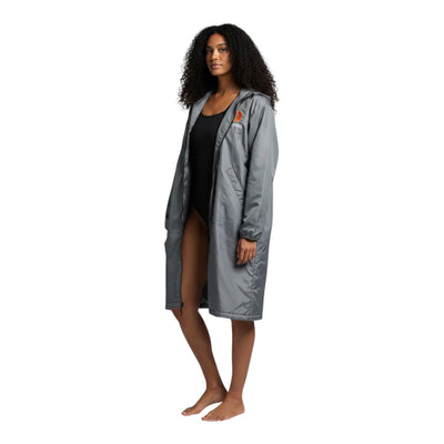 The Swim Guy Online Store grey Dare Aquatics team parka with hood and orange logo. Model wears black leggings and sneakers.
